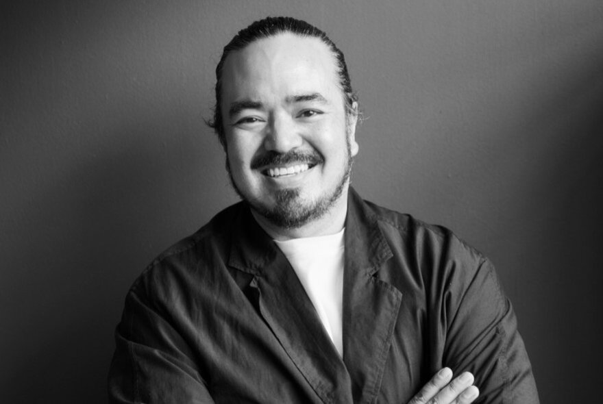 Adam Liaw, smiling with his arms folded.