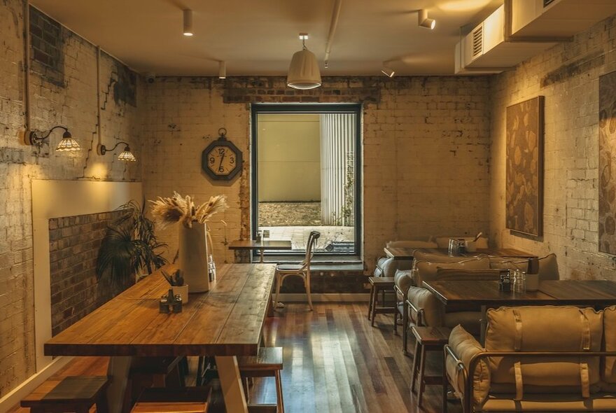 Rustic cafe interior with wooden tables and seating, old fireplace and painted brick walls.