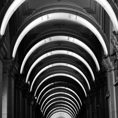 A black and white image of the inside of a building with a vaulted ceiling. 