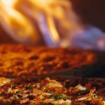 Pizza cooking in a flaming oven.
