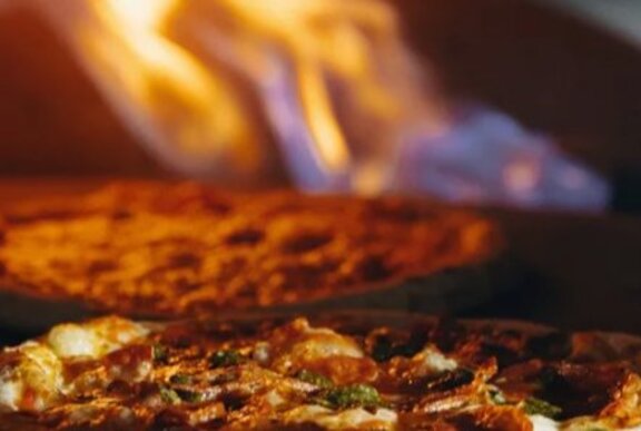 Pizza cooking in a flaming oven.
