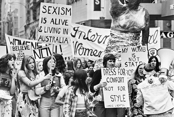 Black and white image of people protesting with banners and placards in the street.
