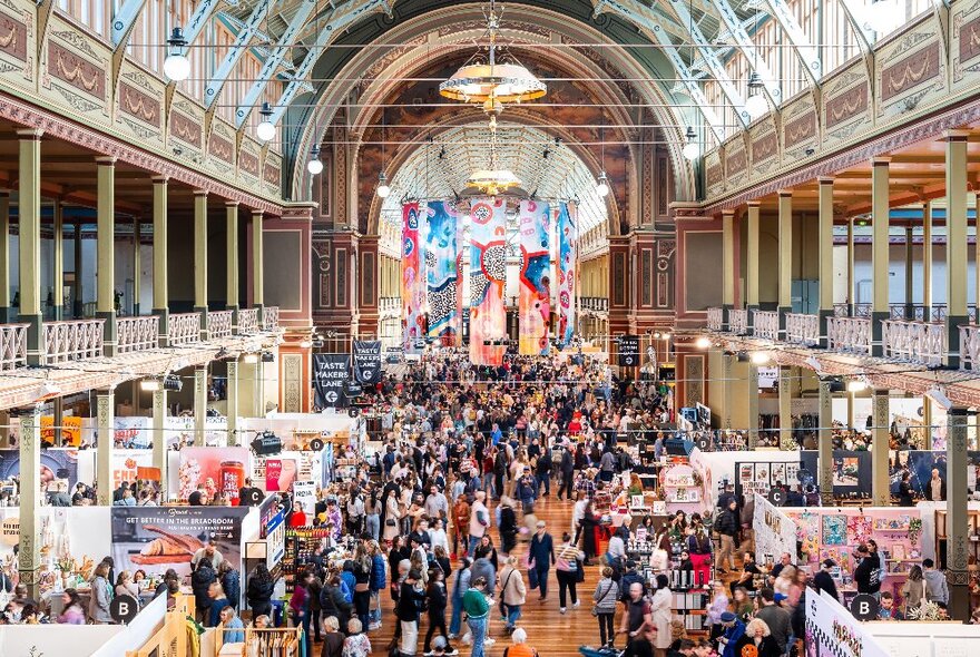 Crowds of people browsing designer stalls and food carts at the Big Design Market inside the Royal Exhibition Buildings.