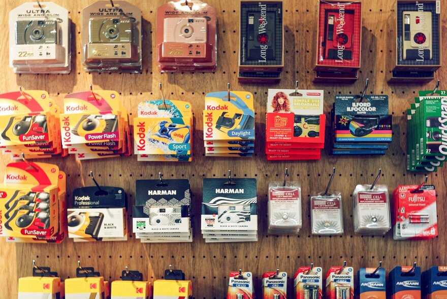 A retail pegboard retail display of 35mm film rolls and disposable or single-use cameras.