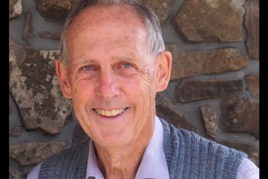 Ex-politician and environmentalist Bob Brown, smiling and looking relaxed in front of a stone wall. 
