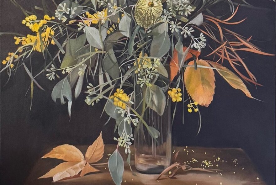 Vase of gum leaves and wattle with autumn leaves.