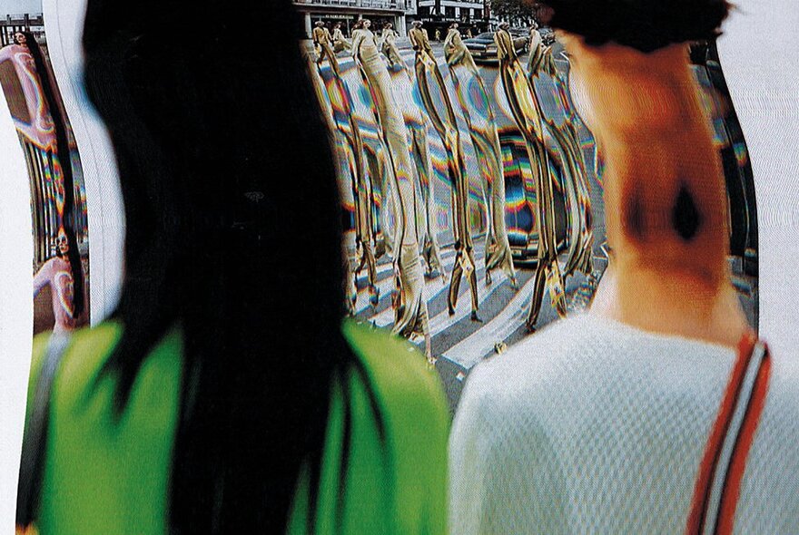 The distorted reflection of two people looking into a curved mirror.