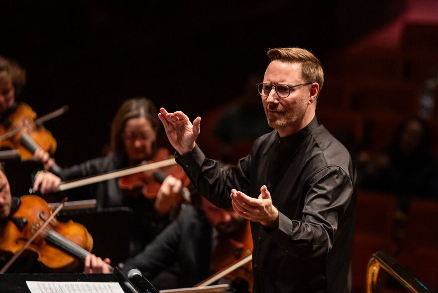 A conductor at work in front of an orchestra. 