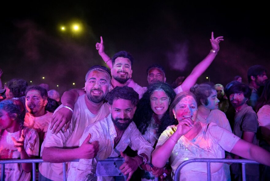 People looking happy leaning on railings at an event at night. 