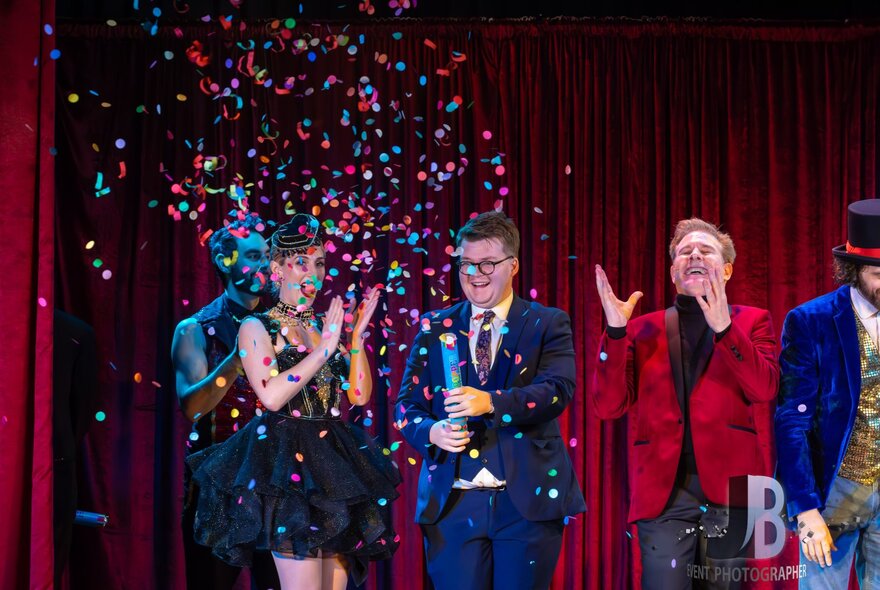 Performers on stage under a cloud of confettil.