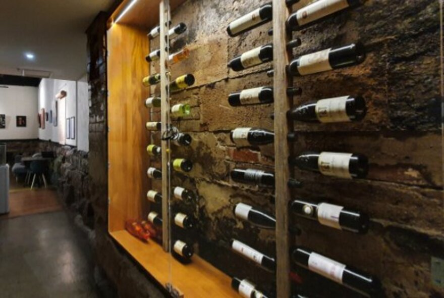 Interior of Life's Too Short Bar, with a rack of wine bottles displayed against an exposed brick wall.