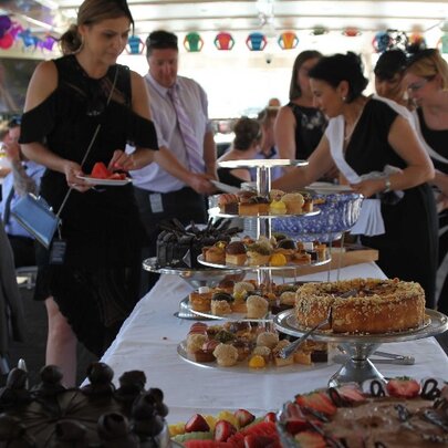 The buffet table on board a boat with people lining up to put food on their plates.