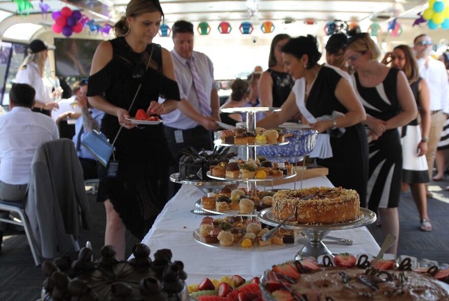 The buffet table on board a boat with people lining up to put food on their plates.
