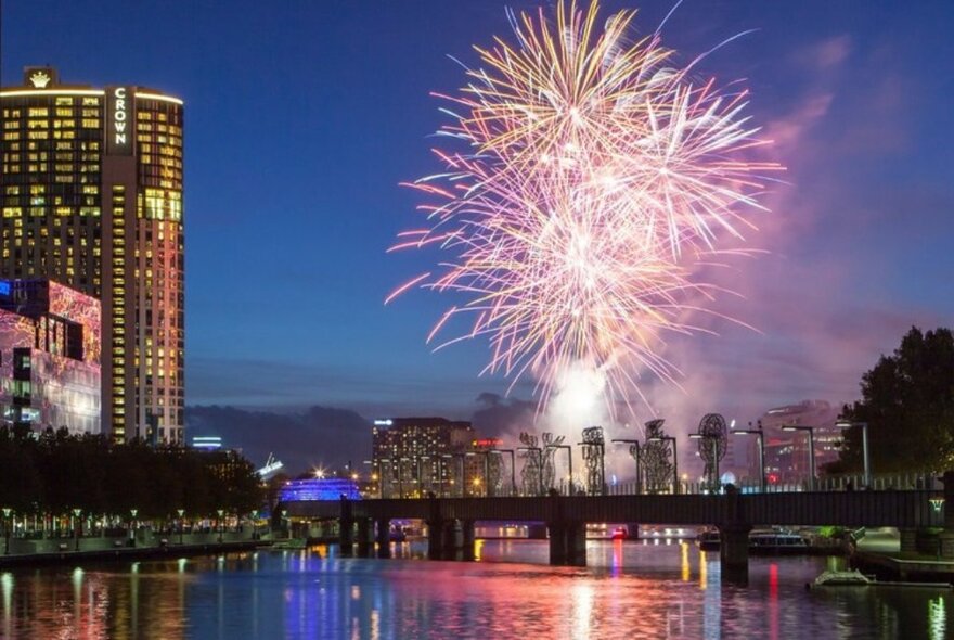 Fireworks exploding above Melbourne's Yarra River and bridges.