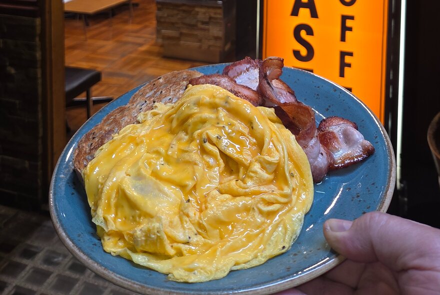 A plate of scrambled eggs and bacon.