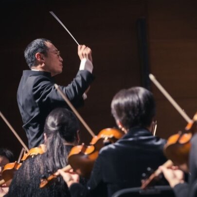 Conductor leading an orchestra of violinists.