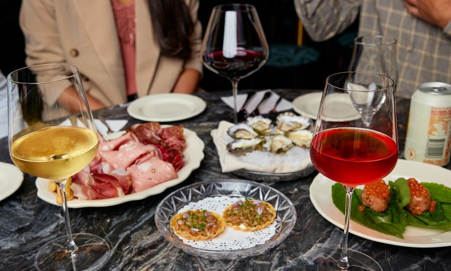 A bar table set with glasses of wine and share plates. 