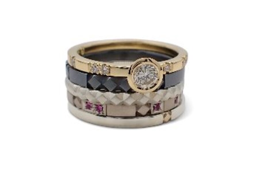 A ring featuring multiple stacks of different materials and a diamond set on top. 