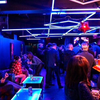 Interior of Miranda Bar with people standing at the bar andor seated at small tables along a wall.