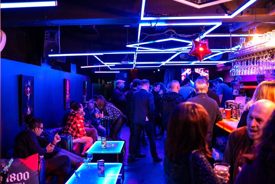 Interior of Miranda Bar with people standing at the bar andor seated at small tables along a wall.