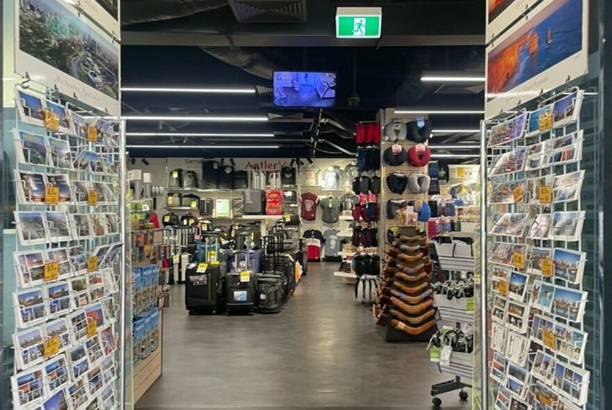 Interior of luggage shop with displays of bags and postcards.