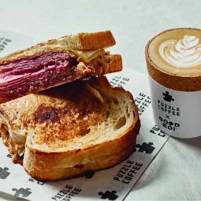A sliced toasted sandwich and a takeaway coffee cup resting on a marble table-top.