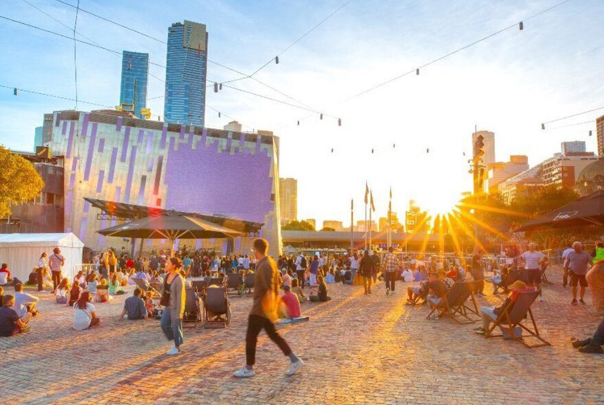 Crowds in Fed Square in the city at sunset.