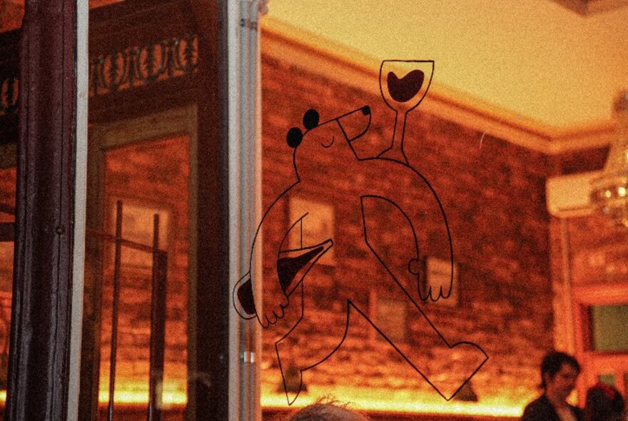 The exterior of Bear's Wine Bar with a bear illustration on the window, a warm glow from within. 