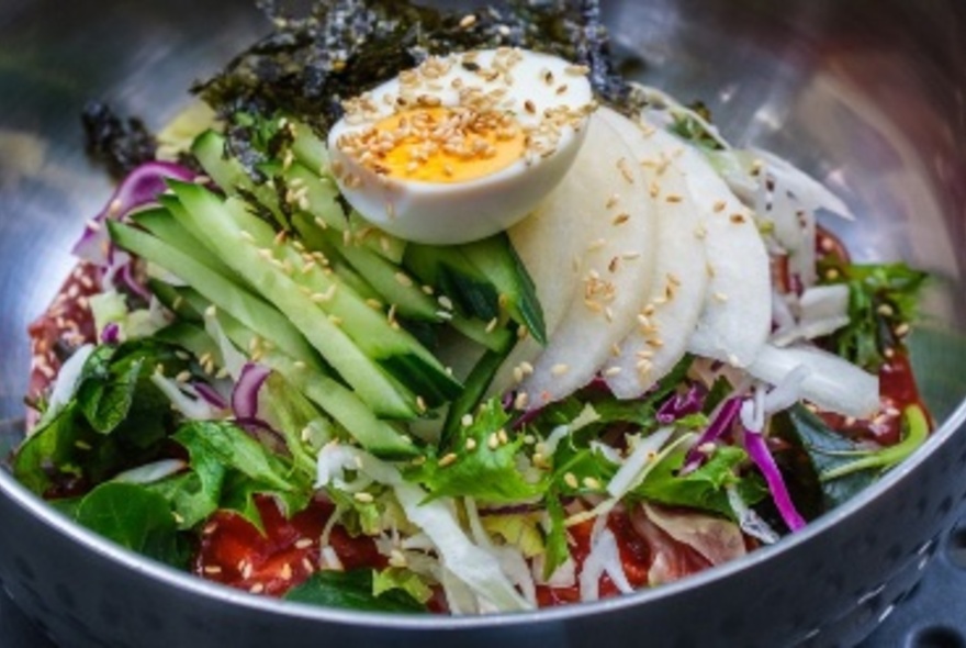 A Korean salad dish with half a boiled egg on top and sesame seeds sprinkled over it.