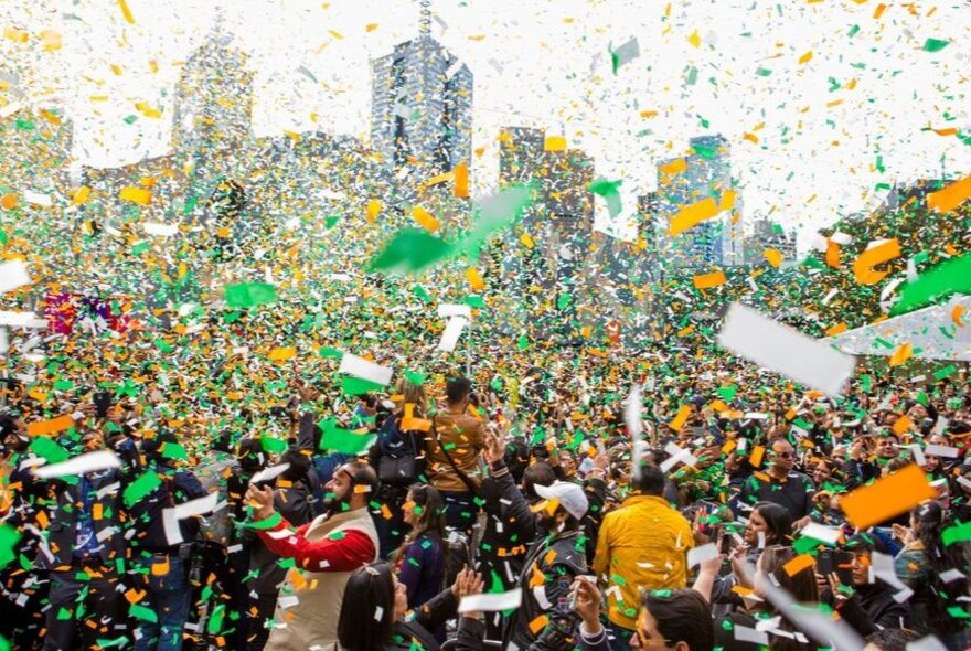 A crowd covered in yellow and green confetti.