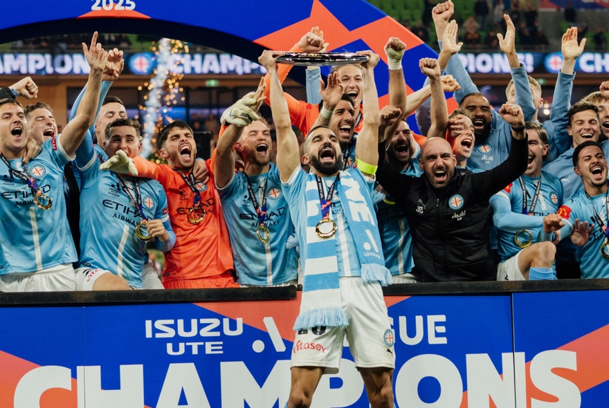 Melbourne City soccer team in pale blue kit cheering wildly with arms in the air.
