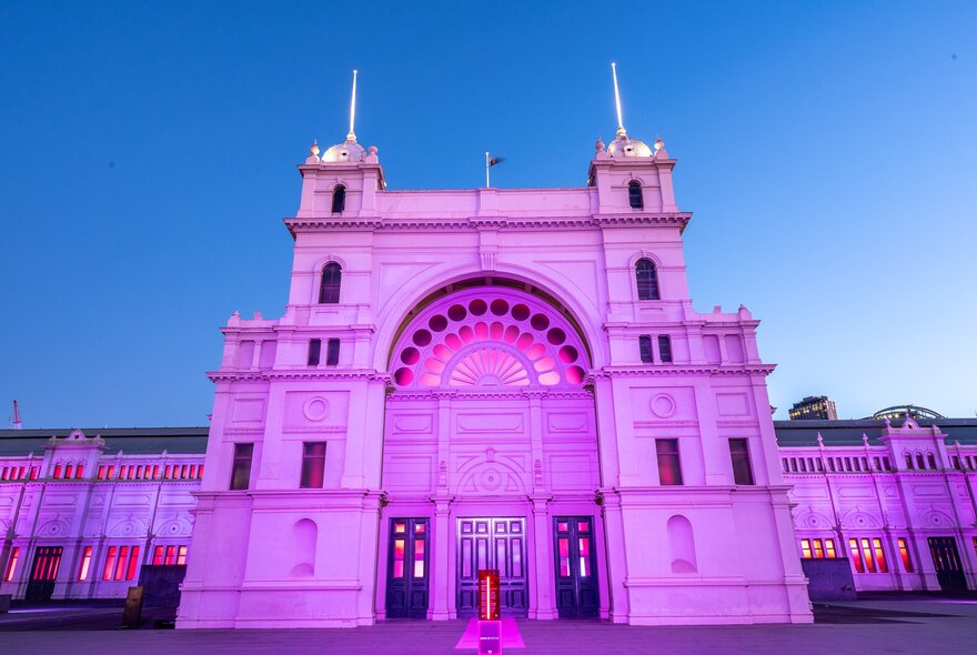 The exterior of Royal Exhibition Building lit up in purple lights at dusk