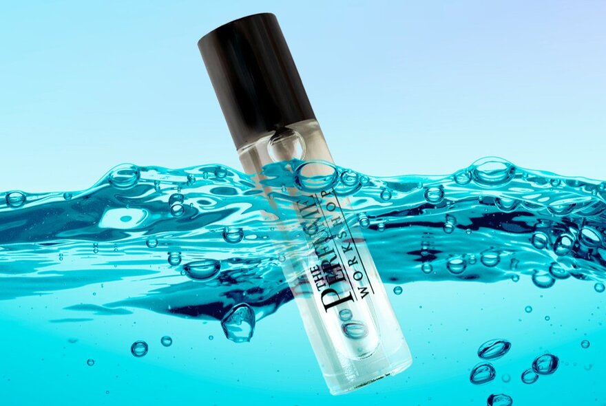 A perfume bottle floating in blue bubbly water.