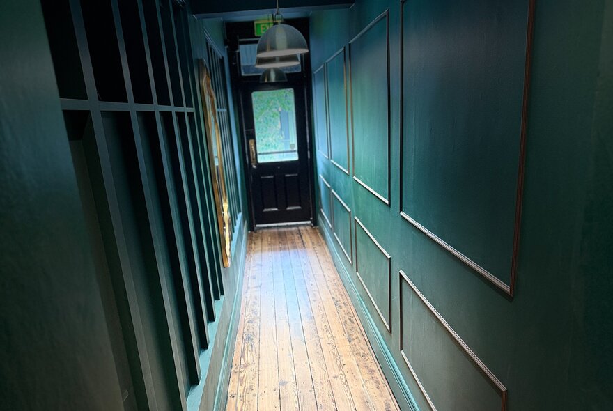 Panelled hallway with wooden floorboards and glass front door.