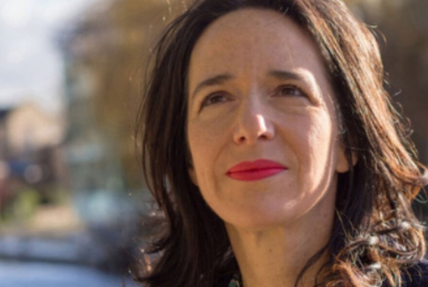 Portrait of author, Elise Valmorbida, with a blurred landscape behind her.