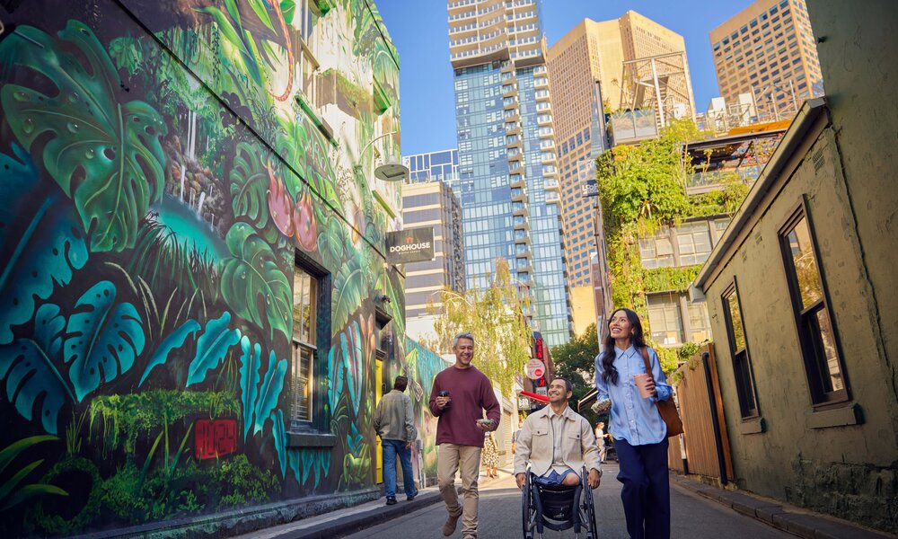 Four people in a laneway with a large wall mural of a jungle.