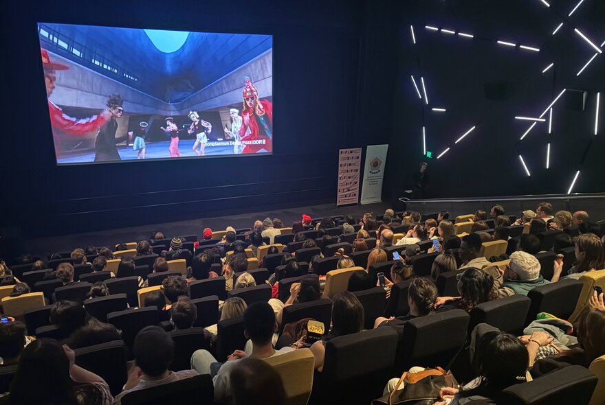 A seated audience in a theatre at ACMI, watching a Korean film on screen.
