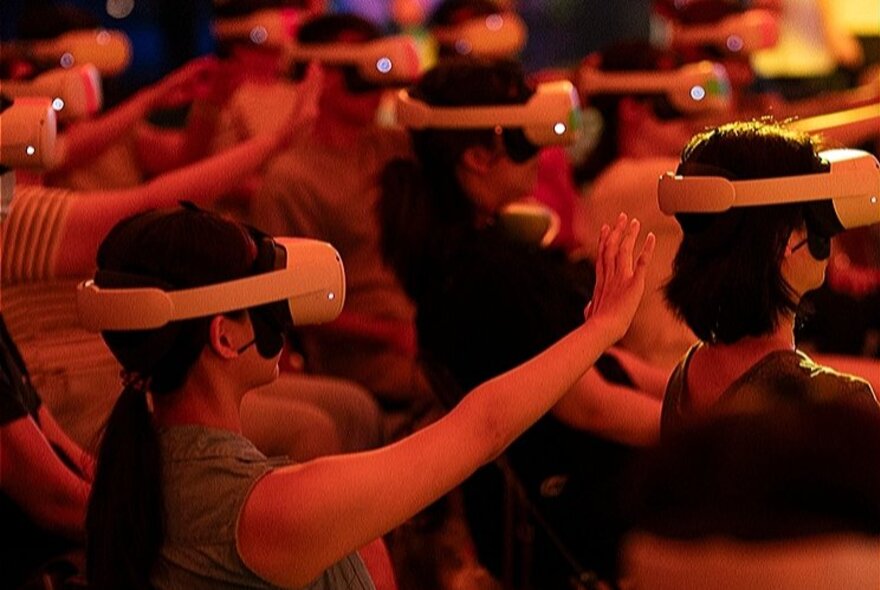 A group of people wearing VR headsets performing a movement in unison. 