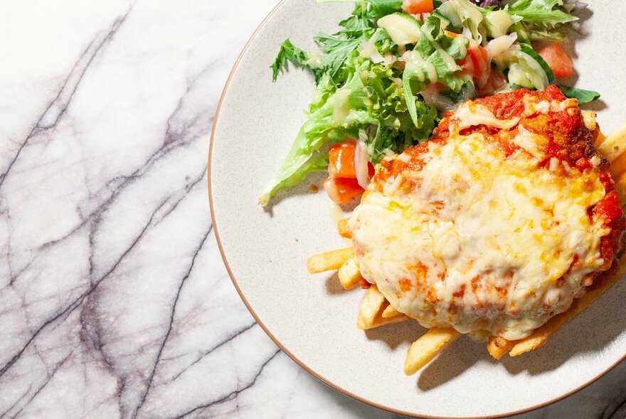 Parmigiana, chips and saladon a plate.