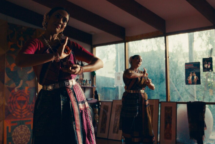 Two Indian women in traditional clothing dancing.
