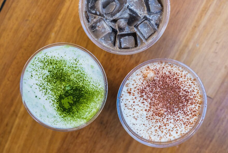 An aerial view of three creamy drinks, including a matcha latte.