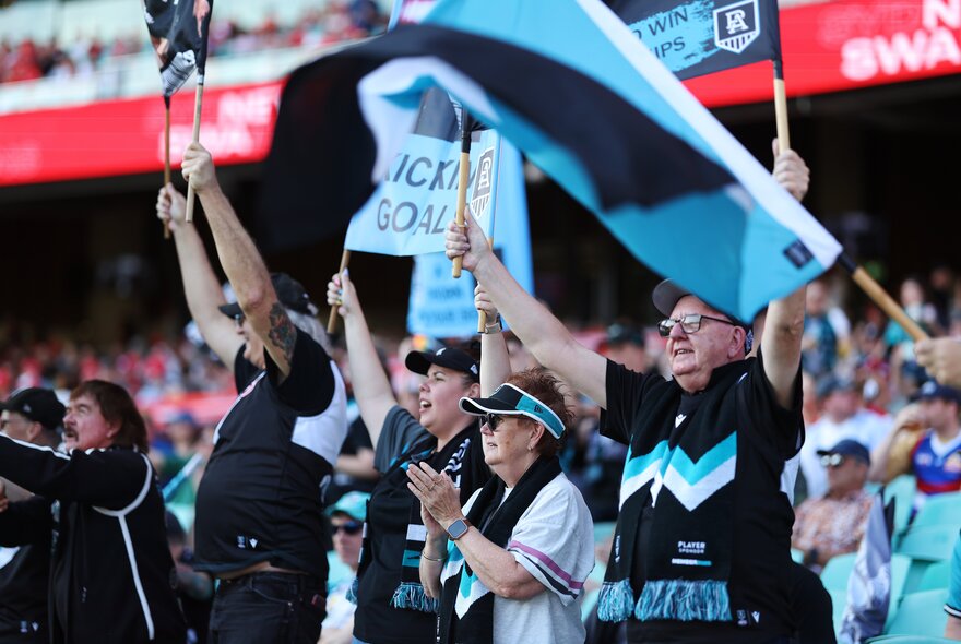 Port Adelaide supporters at a match waving banners. 