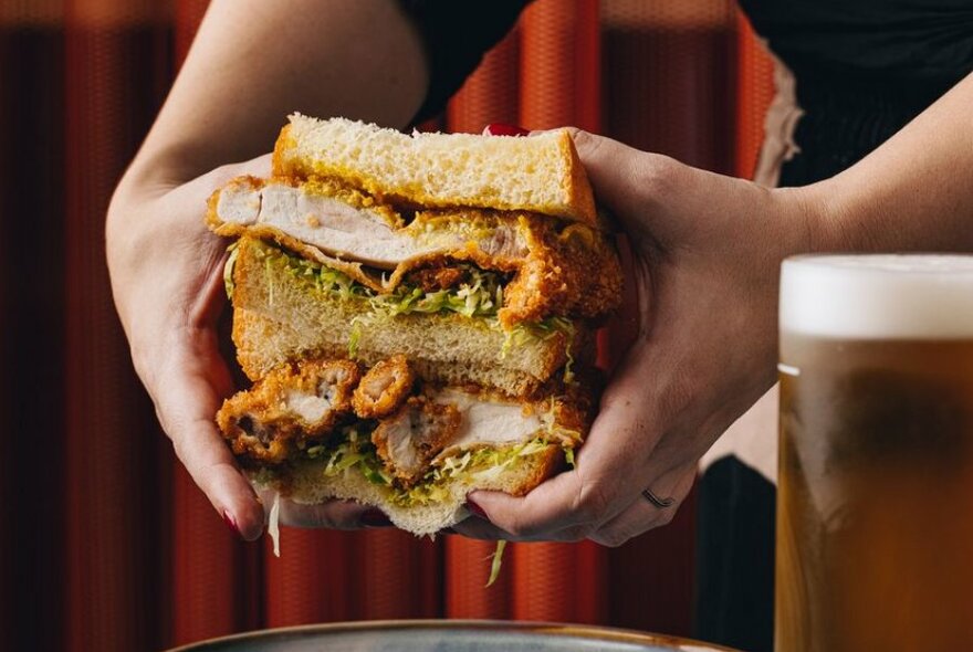 A person holding a fried chicken sandwich with two hands.