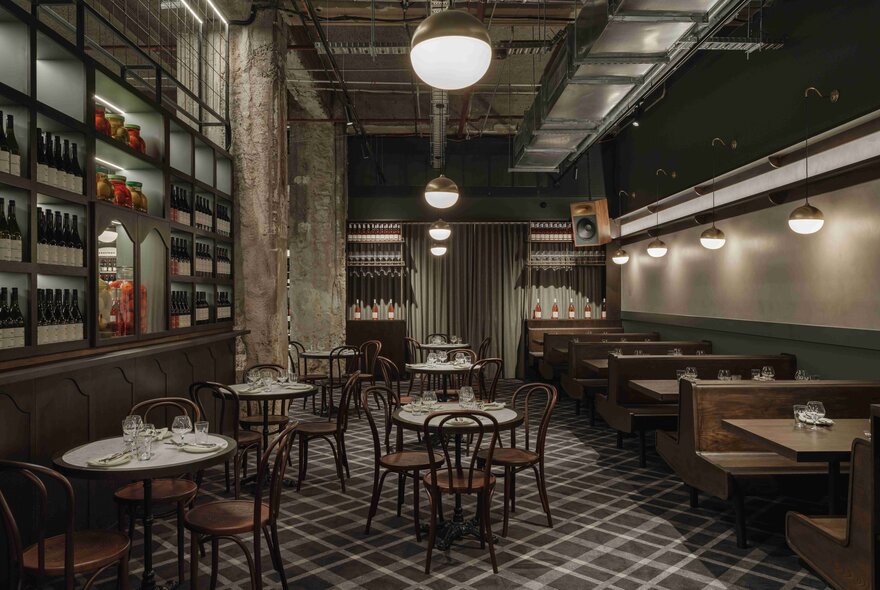 The interior of the Italian-style wine bar with round tables, wooden chairs and booth seating, wine shelves on the left.