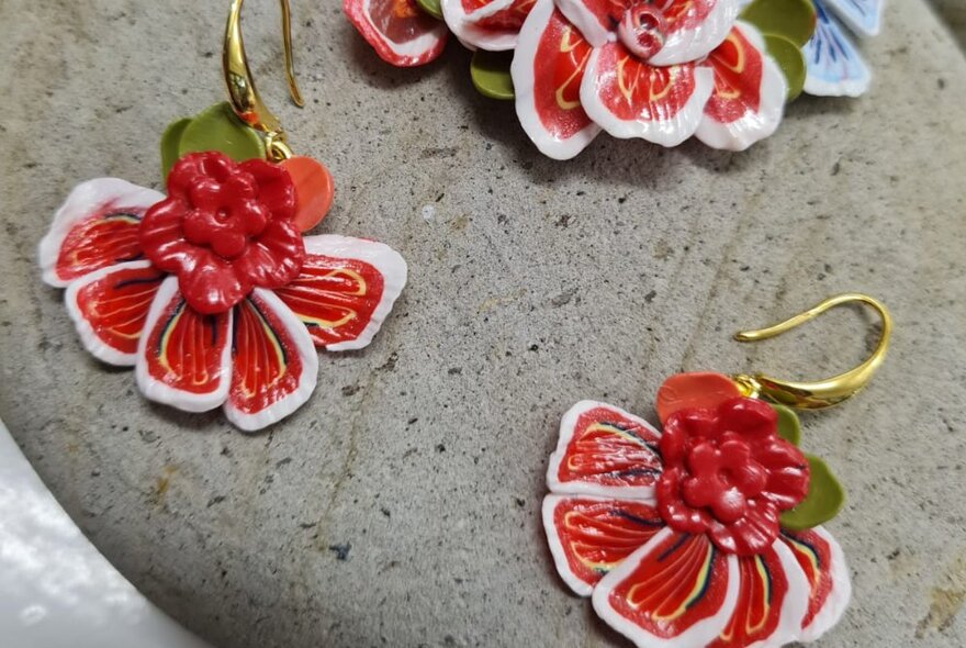 Red coloured earrings that resemble flowers, made from polymer clay.