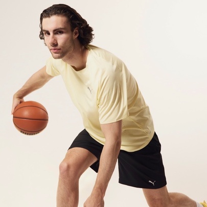 A basketballer in a yellow t-shirt and black shorts bouncing a basketball with his right hand.