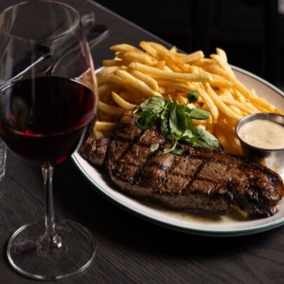 Plate of steak and chips with a glass of red wine.