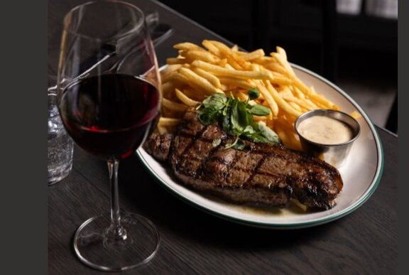 Plate of steak and chips with a glass of red wine.
