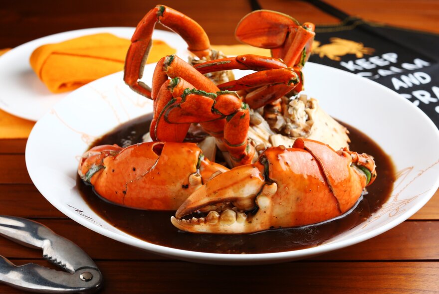 Crab dish in dark sauce with metal crab crackers.