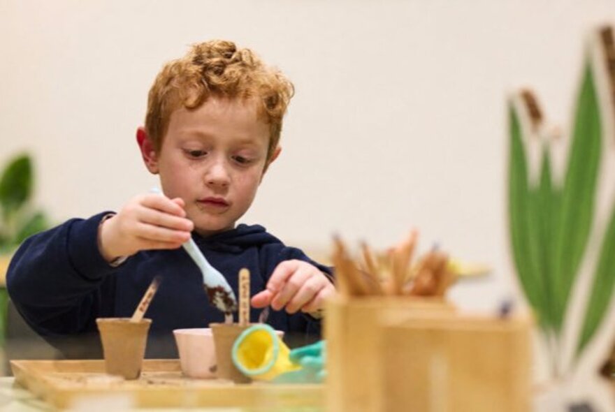 A child playing with pots of paint at an activity table.
